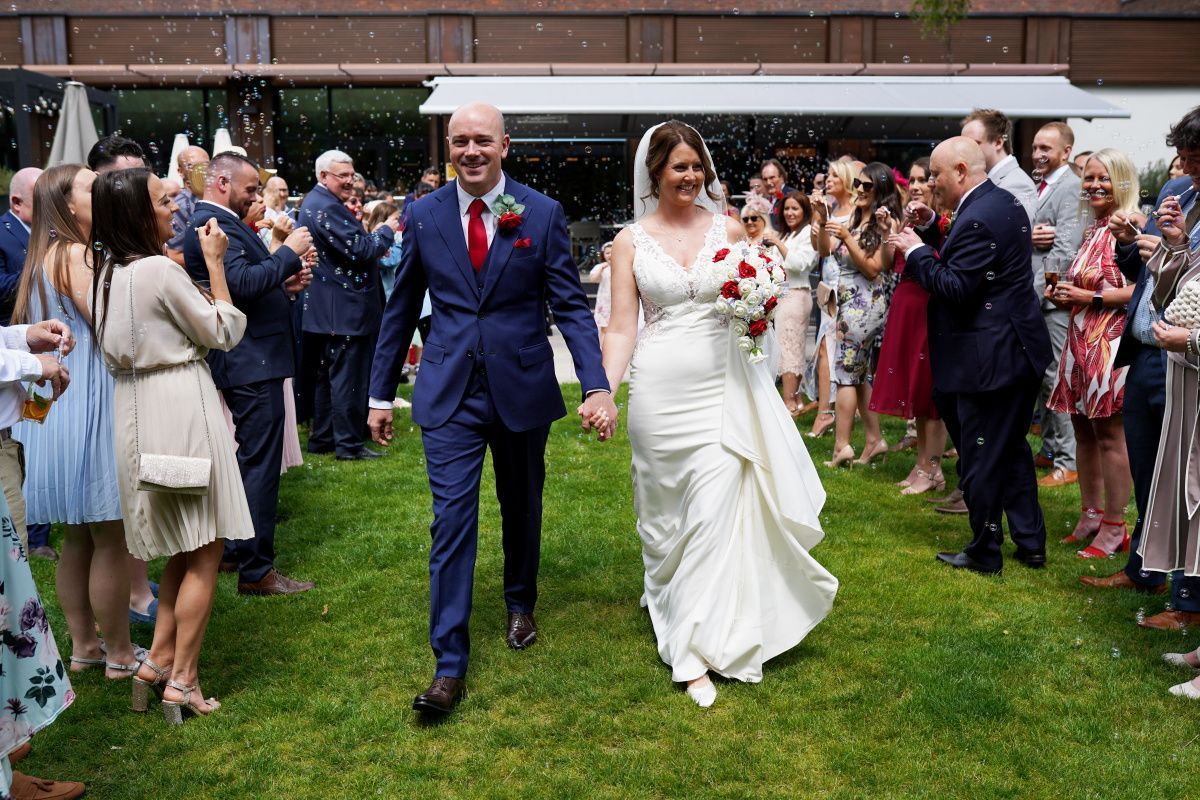 bride and groom walking in gardens smiling.